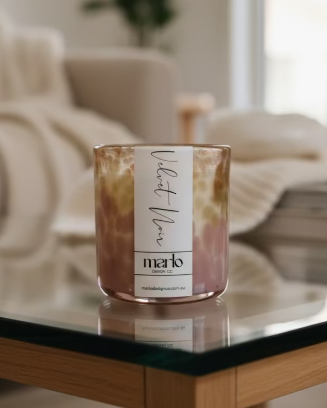 Marlo Design Co. Velvet Noir black raspberry and vanilla scented candle in a decorative blush pink and white honeycomb pattern glass vessel, styled with white orchids and pearls.